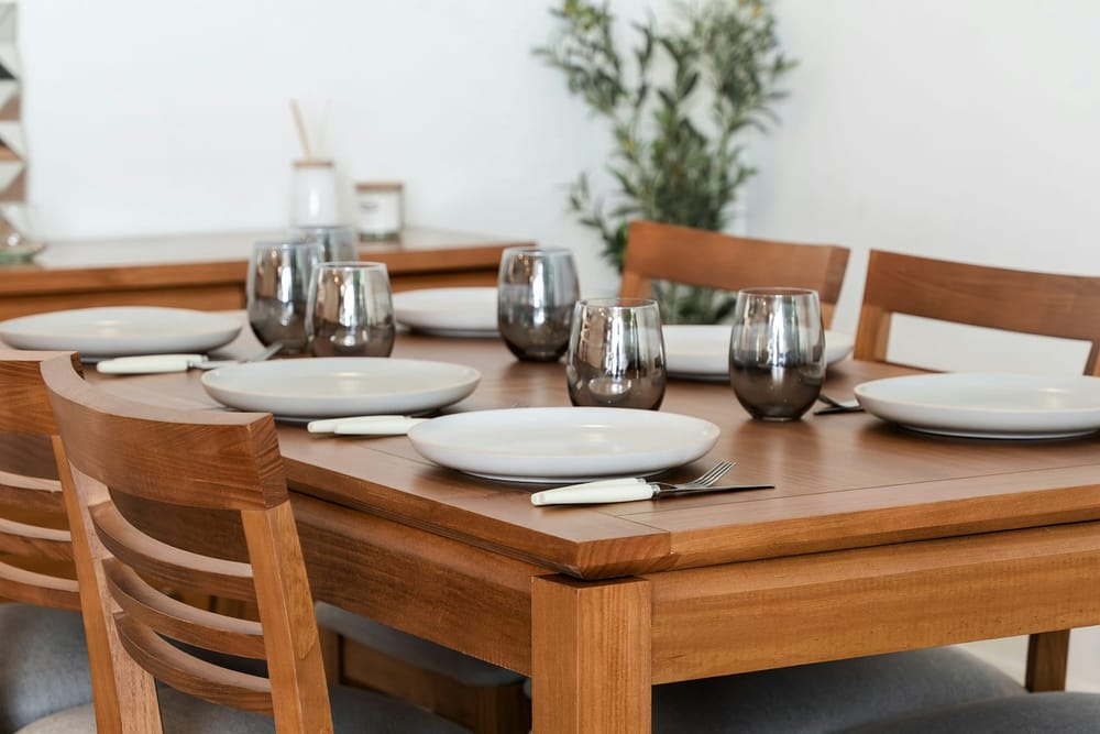 Een gedekte houten eettafel met borden en glazen