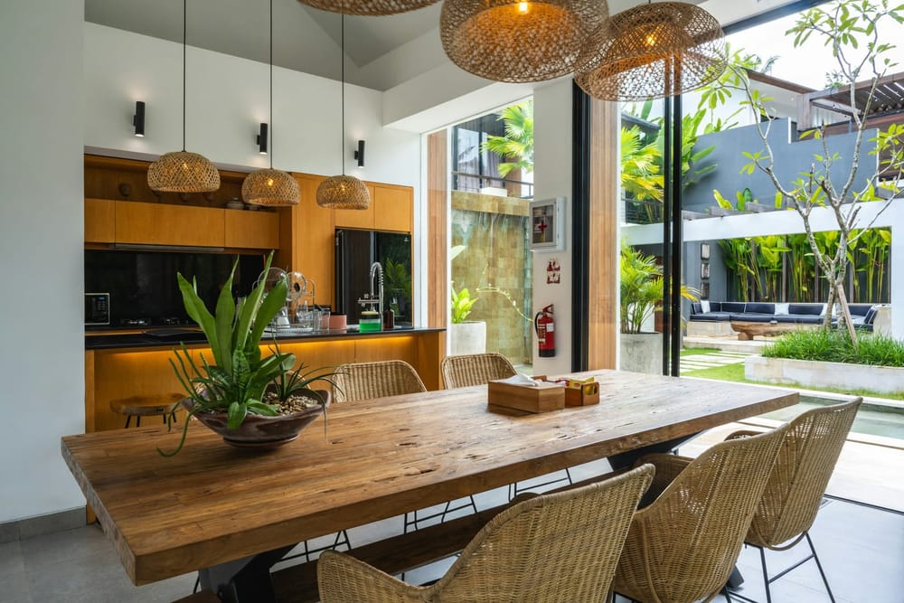 Een eettafel van hout in een lichte keuken met uitzicht op de tuin