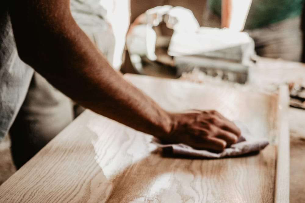 Een hand wrijft olie in een houten blad