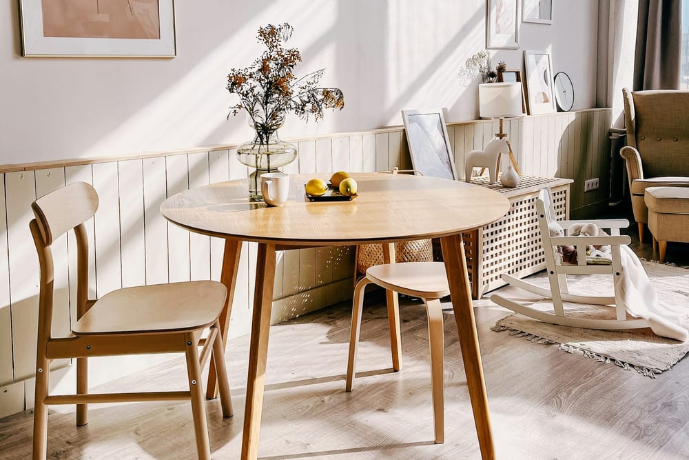 Een ronde houten tafel met stoelen in een lichte kamer